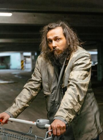 man in gray coat holding a shopping cart