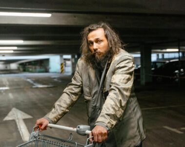 man in gray coat holding a shopping cart