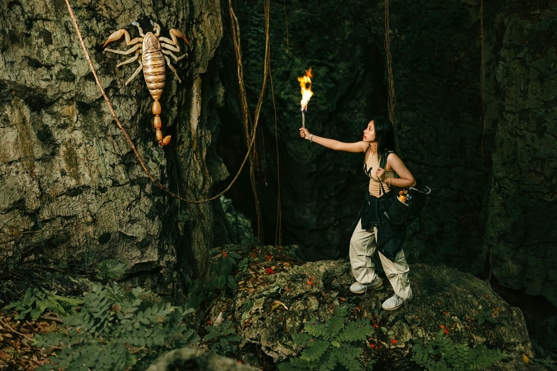 woman with torch looking at giant scorpion in cave